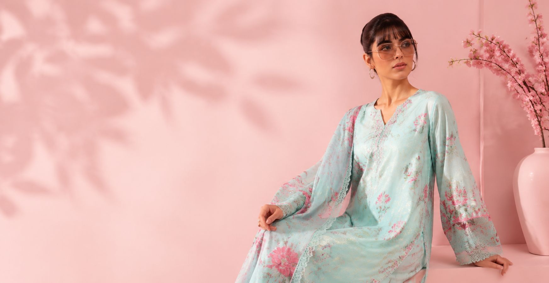 Model wearing a mint floral unstitched suit against a blush pink backdrop